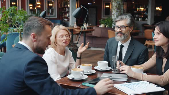 Business Men and Women Talking in Restaurant Then Doing High-five During Successful Talks alt