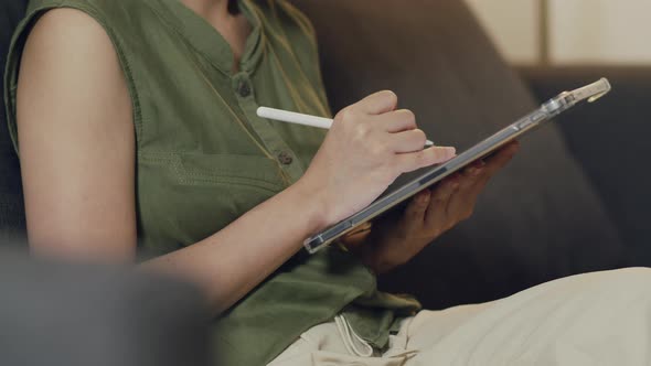 Asian female reading news and trading stock on her digital tablet.