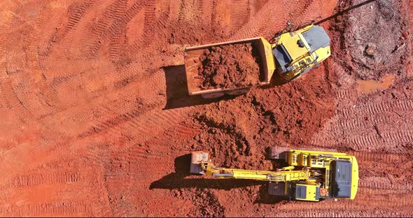 Construction Site Preparation Work with an Excavator Loading Earth Into Dump Trucks for Loading on a alt