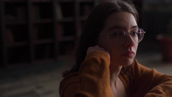Tracking Shot of Pensive Young Woman in Glasses Playing Chess Indoor and Thinking Position Find alt