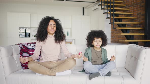 Mixed Race Mother and Son Practice Lotus Position Meditation Sitting on Sofa at Home alt