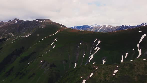 Mountain Ridge of Caucasian Range Partly Covered with Snow and Green Grass alt