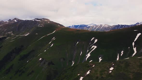 Mountain Ridge of Caucasian Range Partly Covered with Snow and Green Grass