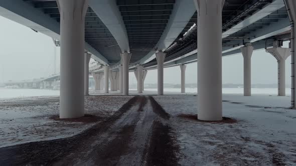 Drone Flying Between Support Pillars Under a Highspeed Road on a Winter Day a Cablestayed Bridge in alt