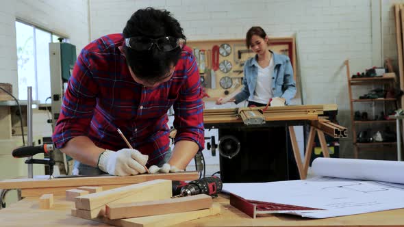 Craftsman marking line on wood on workshop table
