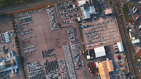 Industrial warehouse with cars in parking lot, top down spinning drone shot. alt