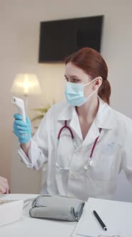 An Orderly Examines an Elderly Patient Measures the Temperature and Fills Out a Medical Record alt