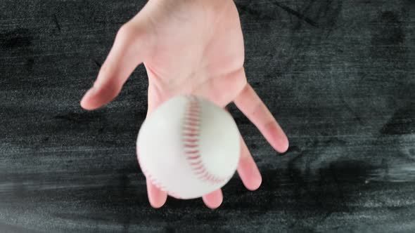 Throwing a baseball up on wooden black background. Close up.