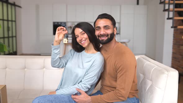 Happy Indian Family Couple Showing New House Keys to Camera While Posing Indoors alt