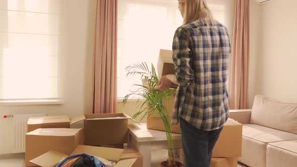 A Woman Brings a Cardboard Box of Things Into the Room