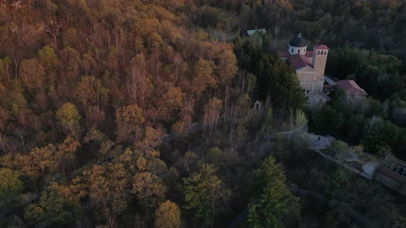 Top down aerial view of church tucked into the side of a mountain in fall. Walking paths to church