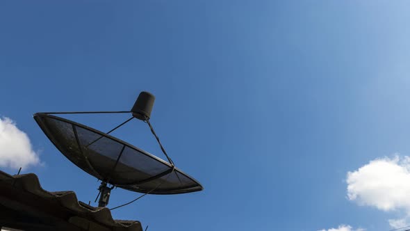 Time-lapse of Black antenna communication Satellite dish with blue sky and cloud background.
