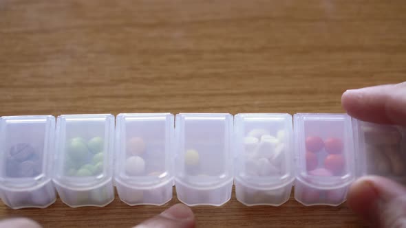 Extreme Close Up of Male Hands Fingers Taking Pills From Plastic Organizer Box alt