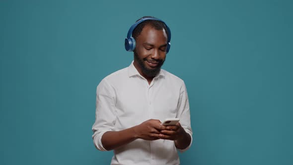 Cheerful Person Listening to Music on Headphones and Using Smartphone alt