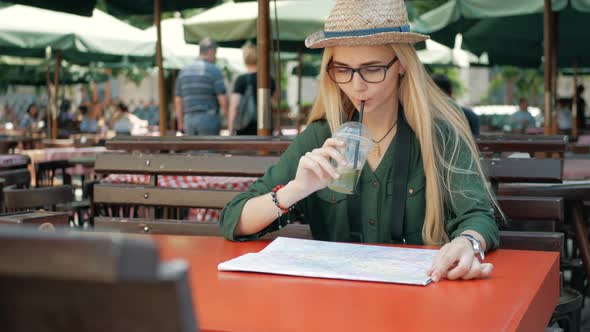 Young tourist woman exploring city map of lviv in cafe and drink while traveling in Ukraine, vacatio