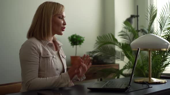 A Close-up Portrait of a Middle-aged Woman with Blond Hair Sitting in an Office on a Wheeled Chair alt