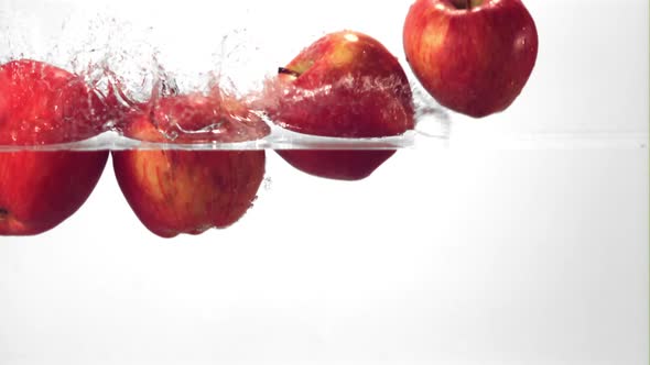 Super Slow Motion Red Apples Fall Into the Water with Splashes alt