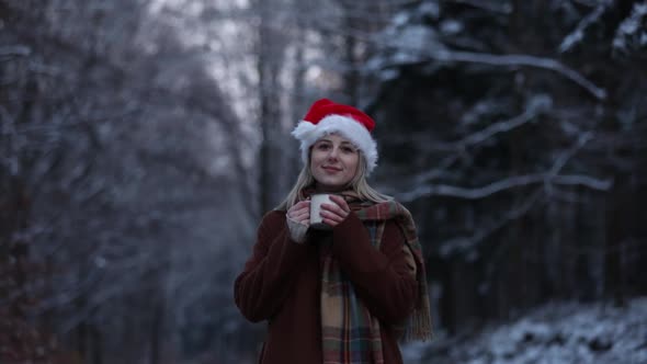 Blonde woman in scarf and Santa hat in a park.