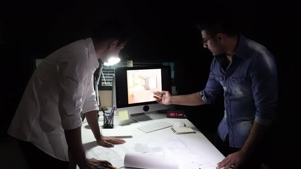 Architect or interior designer team staying late at night working in office discussing blueprints