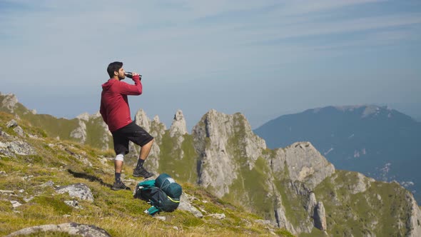 Person Drinking Water on Top of the Mountain with a Scenic View During Autumn 