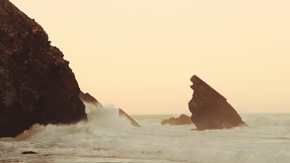 Waves Crashing Against Rocks at Orange Sunrise, Beautiful Rugged Rocky Coastal Scenery and Coastline alt