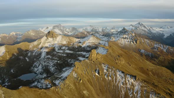 Slow high altitude orbit revealing distant Alpine snowy summits at sunsetAutumn colors, Valais - Sw alt