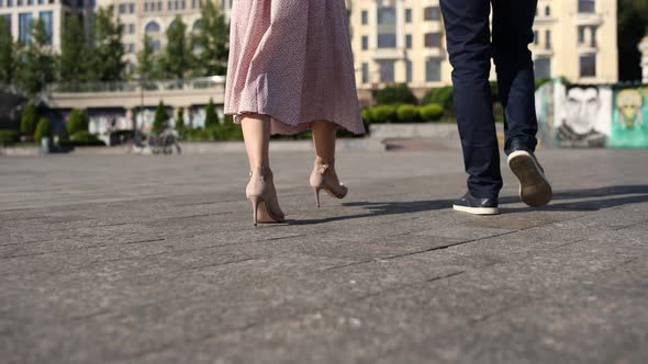 a man with a woman walk on the asphalt in the city legs close-up shoes