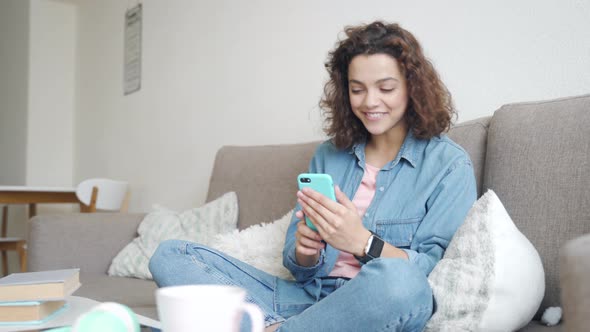 Hispanic Young Woman Using Smartphone App for Online Conference Sitting at Home alt