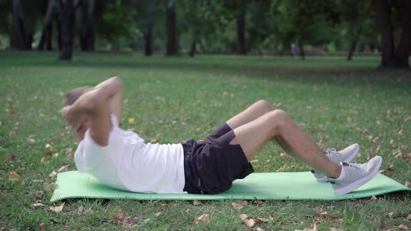 Wide Shot of Fit Caucasian Sportsman Pumping Press on Exercise Mat Outdoors. Morning Workout of alt