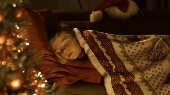 Cute boy sleeping on the sofa and waiting for Santa