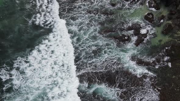 Top down aerial view of giant ocean waves crashing and foaming in coral beach alt