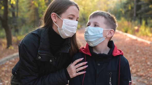 Happy Woman and Boy Wearing Protective Medical Masks at the Park