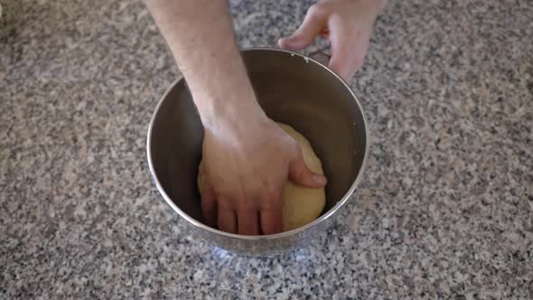 Placing a sourdough ball into a metal mixing bowl with some oil, the dough is turned in the oil befo alt