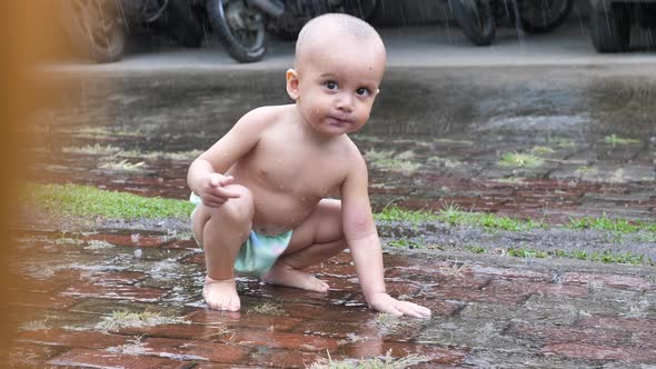 Handsome Little Baby Boy Crawling and Sitting Under the Rain Outside the Garage