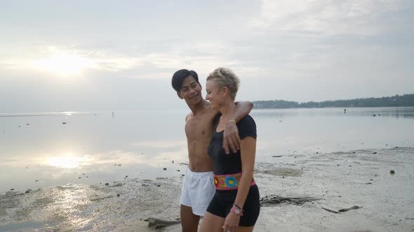 Happy Couple with Age Difference Talking and Walking on a Beach By the Sea at Sunset alt