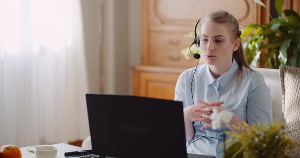 Sales Representative in Headset Speaking To Client and Making Video Conference Call on Laptop alt