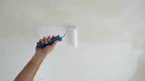 A Painter Paints The Ceiling With White Paint In A New Apartment, A Specialist Works With Paint
