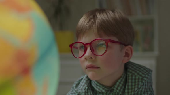 Close Up of Preschool Boy Studying Earth Globe alt