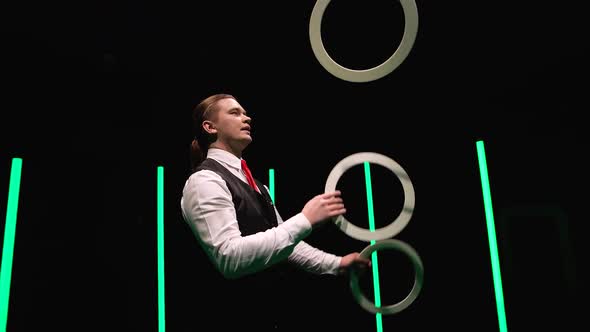 Camera Rotates Around Professional Male Juggler Juggling White Rings alt