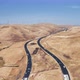 Busy Traffic Along a Winding Road Among Golden Hills. Wind Generators Are Visible in a Distance - VideoHive Item for Sale