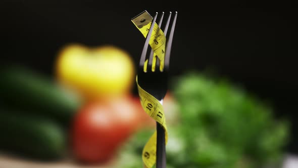 Yellow Measuring Tape on the Fork and Fresh Vegetables on a Wooden Cutting Board alt