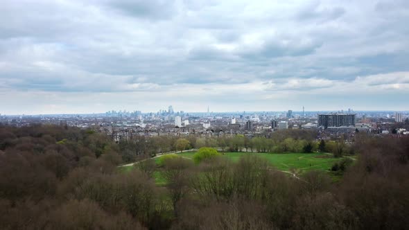 Drone shot flying over Hampstead Heath park with London in backdrop alt