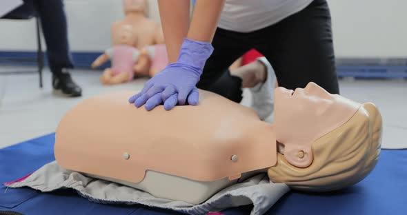 Woman Demonstrating CPR on Mannequin in First Aid Class alt