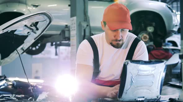 Car Mechanic Uses His Laptop at Work alt