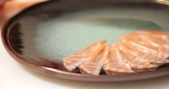 Chef Turned The Plate And Carefully Putting The Thinly Sliced Raw Meat Of Salmon For The Sashimi Dis alt