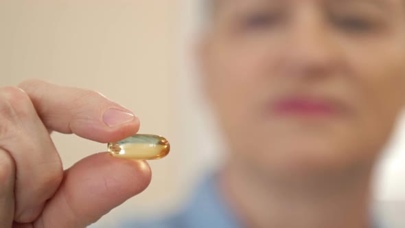 Woman Holding Fish Oil Capsule in Hand