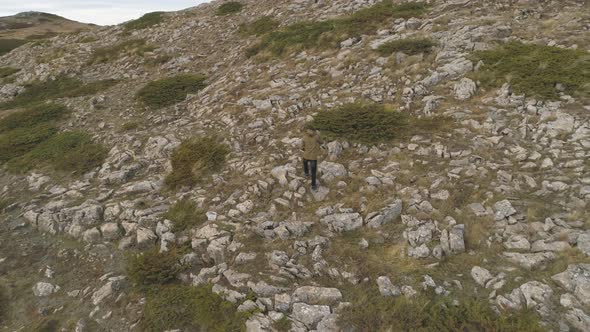 Man Tourist Walk on Sharp Rock Peak. Alone Hiker in Green Jacket Enjoy View.