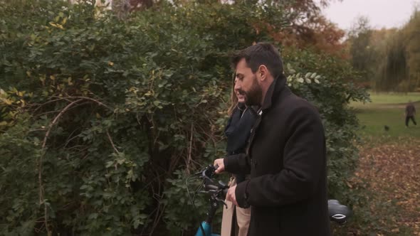 Handsome young couple in the autumn park with electrical bicycle