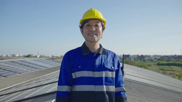 Portrait Asian engineer on field of photovoltaic solar panels solar cells on roof top factory.