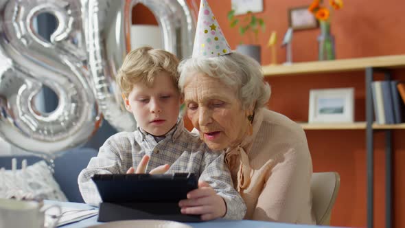 Kid Playing on Tablet with Grandma on Birthday Dinner at Home alt